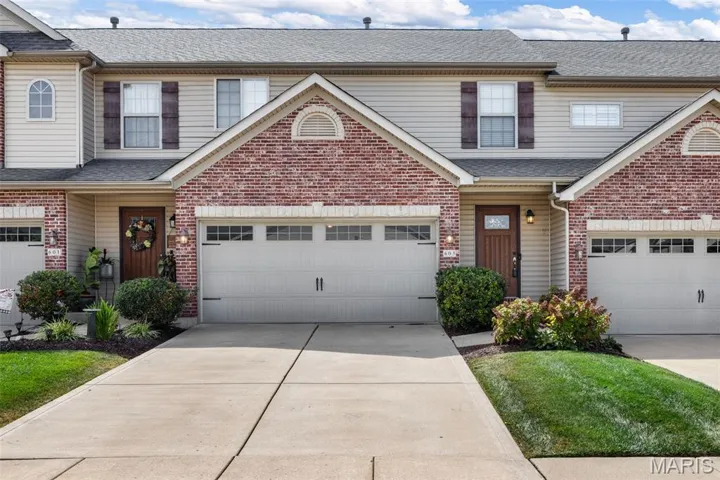 Traditional-style home with a shingled roof, a garage, and driveway