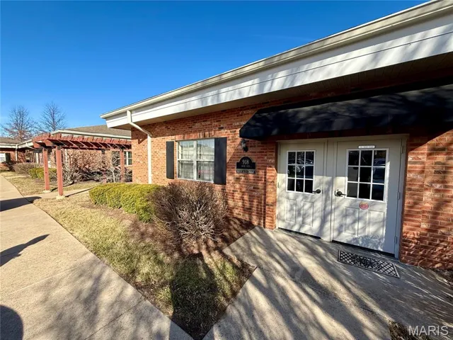 Doorway to property with brick siding, a pergola, and french doors