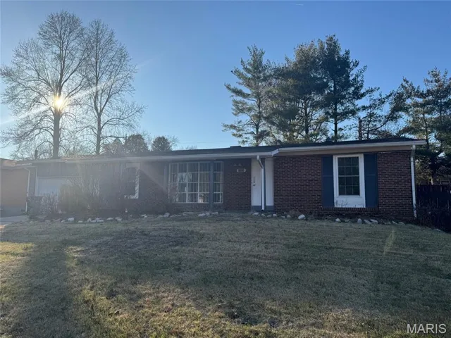 Ranch-style home featuring brick siding, a front lawn, and a garage