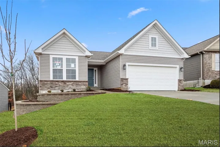 View of front of property with a front yard, driveway, a garage, and brick siding