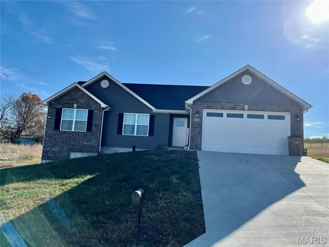 Ranch-style house with driveway, brick siding, a garage, and a front yard
