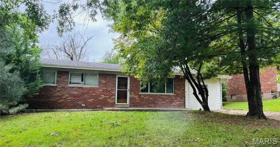 Back of property featuring a lawn and brick siding