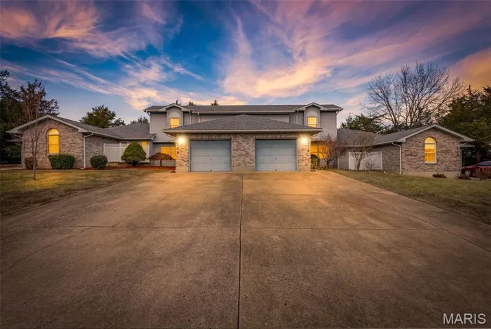 Traditional-style home with a yard, driveway, an attached garage, and brick siding