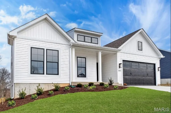 Modern farmhouse featuring covered porch, board and batten siding, a garage, and a front yard