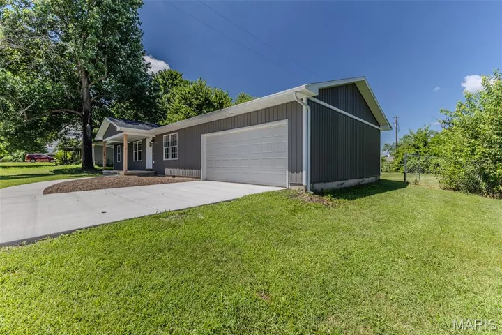 Ranch-style home featuring an attached garage, concrete driveway, and a front yard