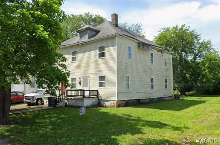 View of home's exterior featuring a chimney, a wooden deck, and a yard
