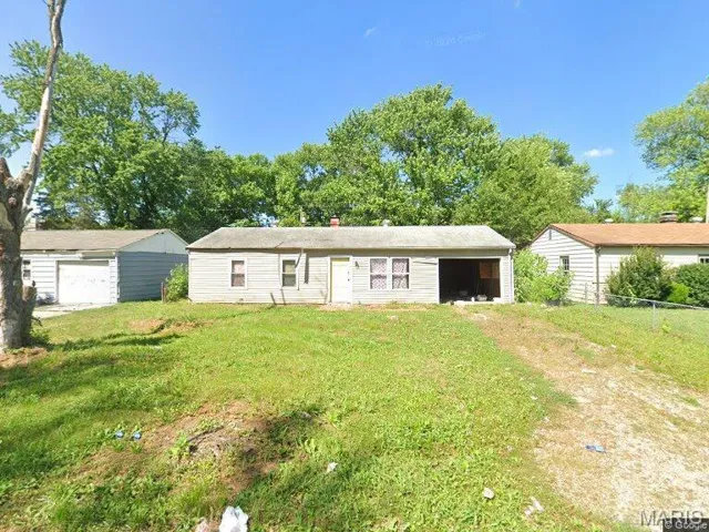 Back of property with an outdoor structure, a detached garage, and a chimney