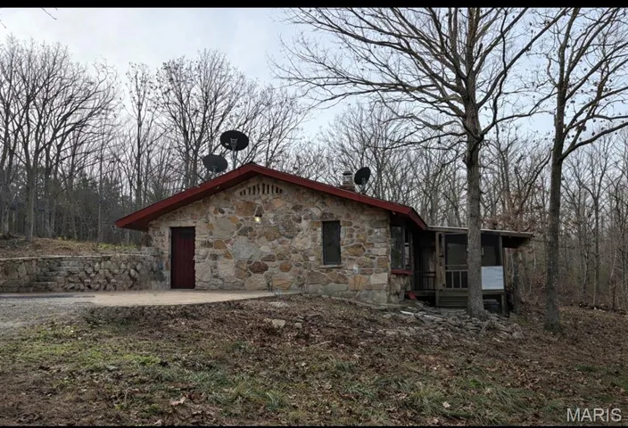 View of front of house with a sunroom and stone siding