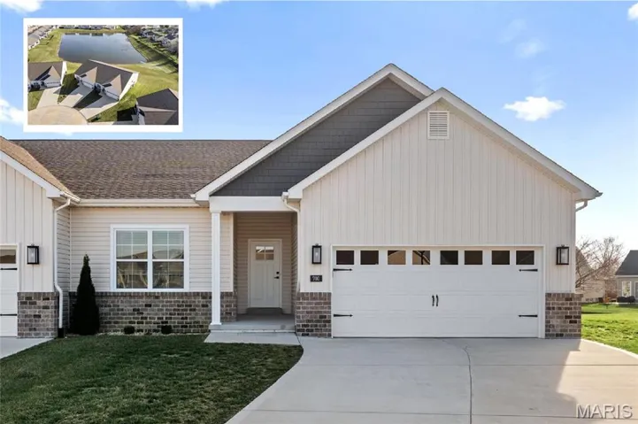 View of front of home featuring a front lawn, concrete driveway, a garage, board and batten siding, and brick siding