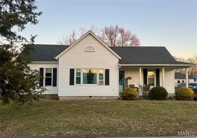View of front facade with a shingled roof, covered porch, and a front yard