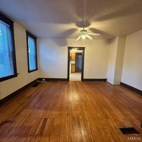 Spare room featuring a textured ceiling, dark wood-style flooring, and a ceiling fan