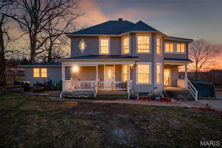 View of front of home with covered porch and a lawn
