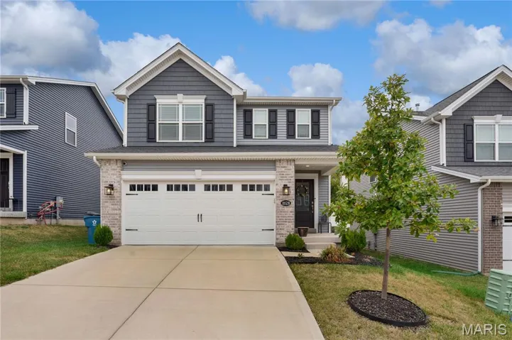 View of front of home with driveway, a front lawn, an attached garage, and brick siding