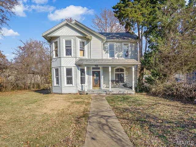 Victorian house with a front lawn and a porch