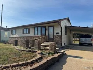View of front of home featuring driveway, an attached carport, and brick siding
