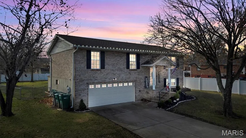 Bi-level home with concrete driveway, brick siding, and a garage