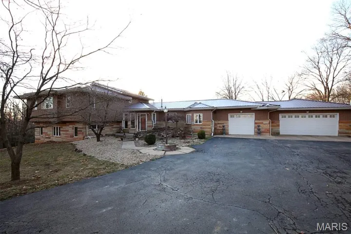 Split level home featuring stone siding, driveway, and an attached garage
