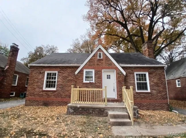 View of front facade featuring brick siding and a chimney