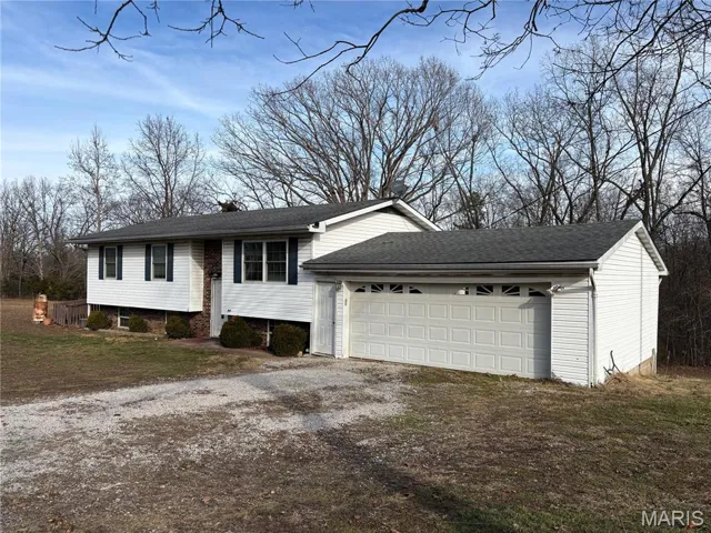 View of front of house featuring driveway, roof with shingles, and an attached garage