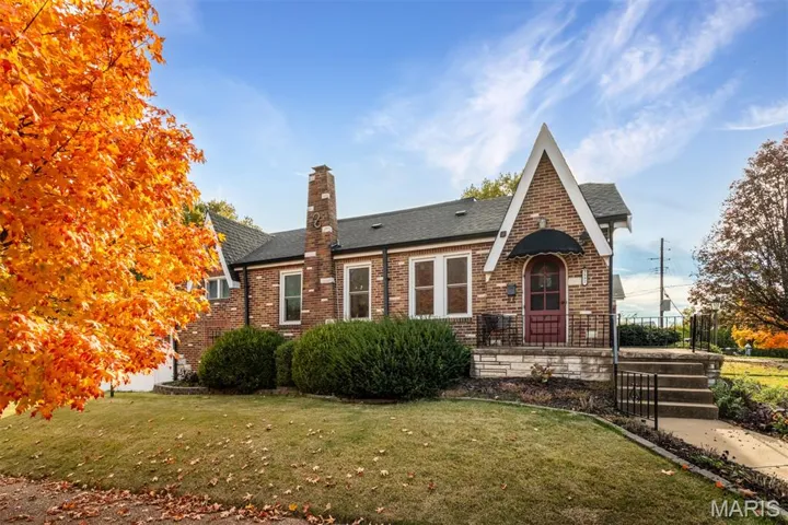 View of front of property with brick siding, a chimney, a front lawn, and a shingled roof