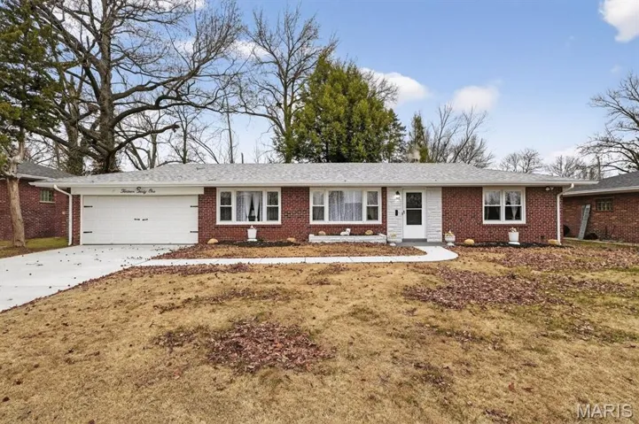 Ranch-style home featuring brick siding, new concrete driveway, and a garage door