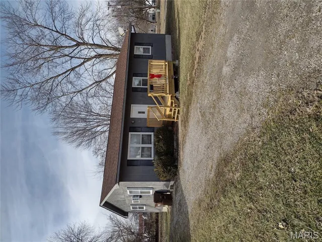 Ranch-style home featuring a wooden deck, a front yard, and a shingled roof