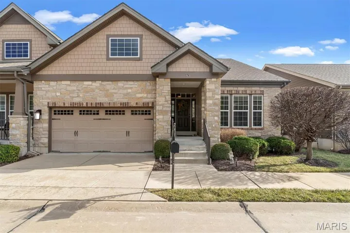 Craftsman-style house featuring stone siding, concrete driveway, and a garage