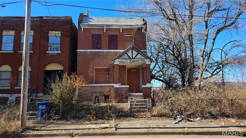 View of front facade featuring brick siding, a fenced front yard, and a gate