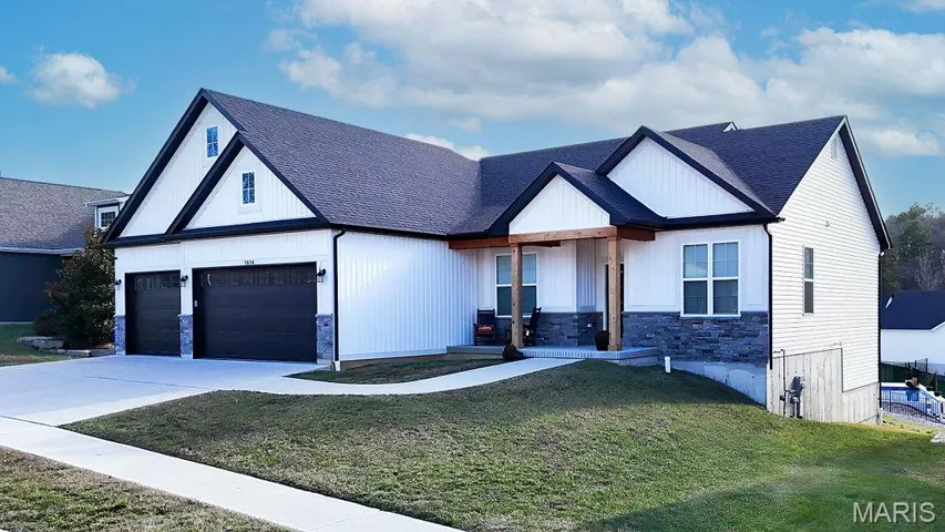 Modern inspired farmhouse with a front lawn, covered porch, roof with shingles, a garage, and stone siding