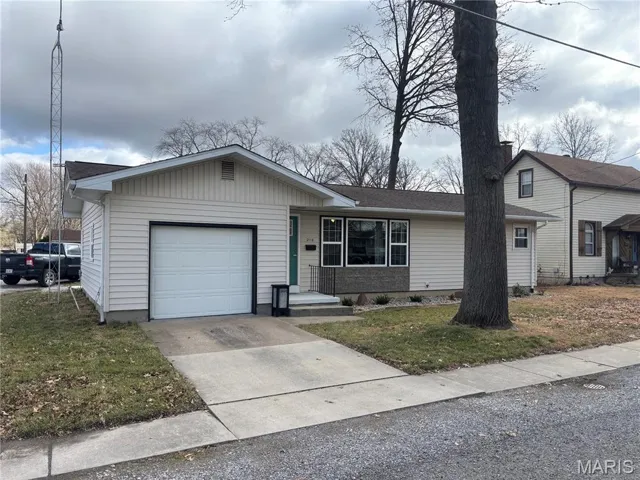 Single story home featuring driveway, a front lawn, and an attached garage
