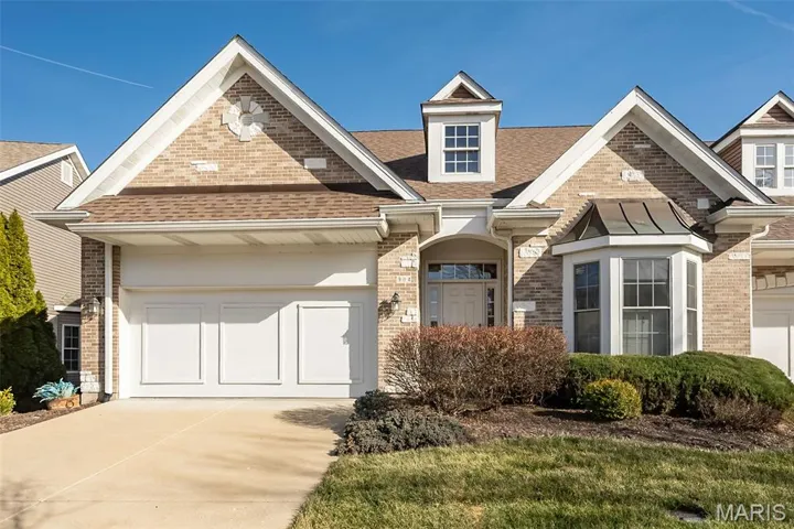 View of front facade with concrete driveway, brick siding, a shingled roof, and an attached garage