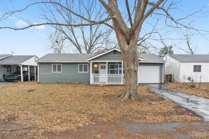 Ranch-style home featuring a chimney, asphalt driveway, covered porch, a garage, and roof with shingles
