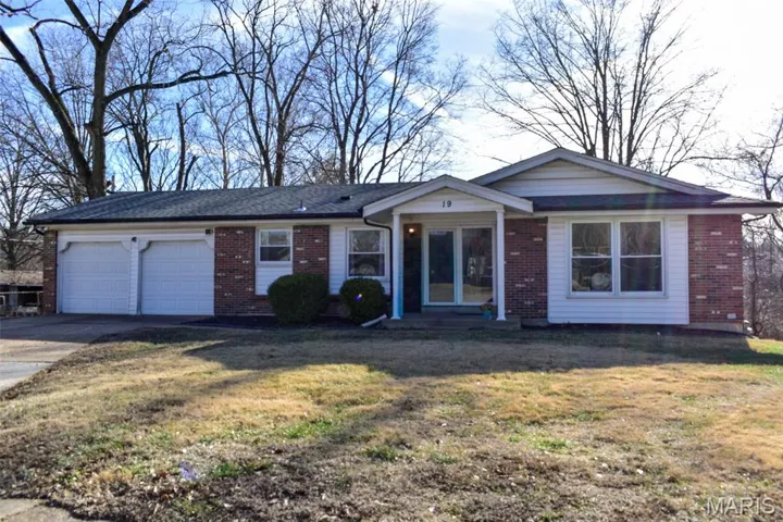 View of front of house featuring brick siding, driveway, a front yard, and a garage