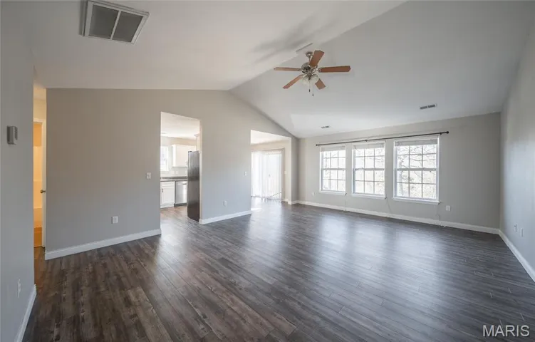 Unfurnished living room with dark wood finished floors, vaulted ceiling, and ceiling fan