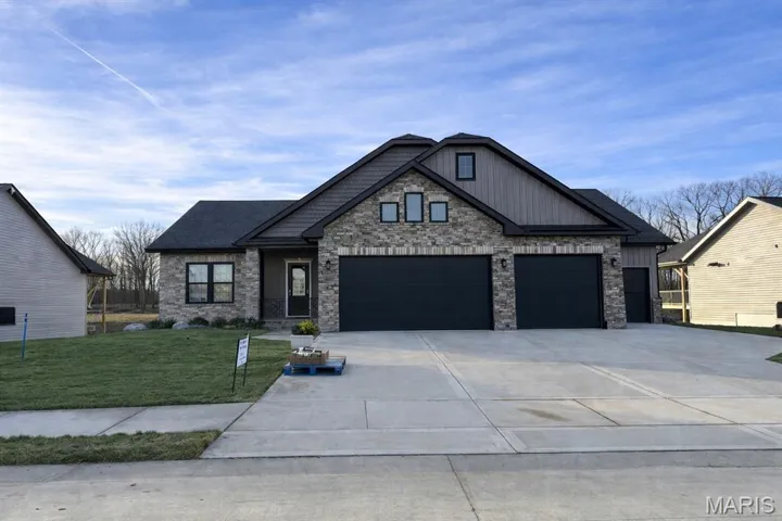 Craftsman house featuring a front yard, driveway, a garage, board and batten siding, and stone siding