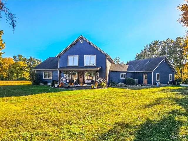 Rear view of property with a lawn and covered porch