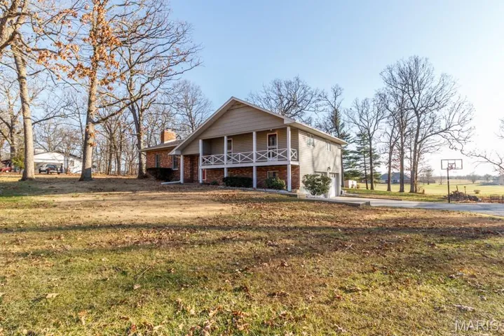 View of front of house with a chimney, brick siding, driveway, a front yard, and a garage