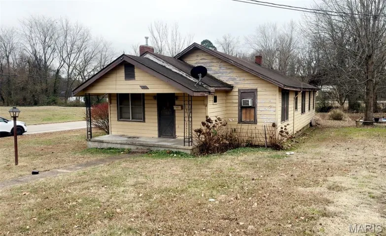 Bungalow with covered porch, a front lawn, and a chimney