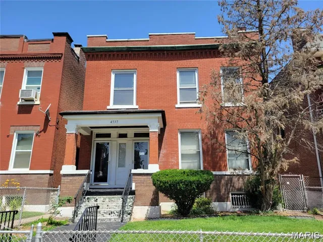 View of front of home with brick siding, a fenced front yard, and a gate