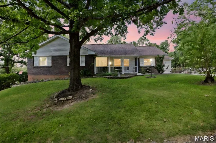 Back of house at dusk with a porch and a lawn