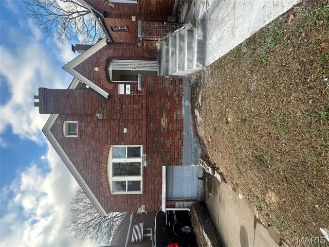 View of front of house featuring brick siding, concrete driveway, a chimney, and an attached garage