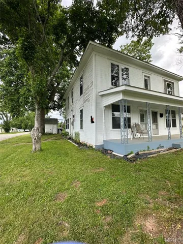 Traditional style home with covered porch and a front yard