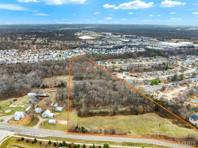 Aerial view of property and surrounding area with property parcel outlined and nearby suburban area