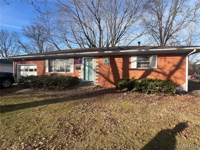 Ranch-style home with brick siding, a garage, and a front lawn