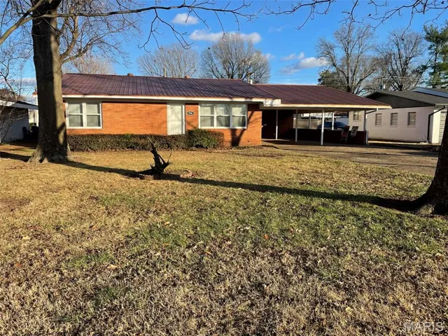 Ranch-style house with a carport, a front lawn, and a metal roof