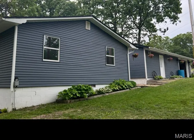 View of property exterior featuring a lawn and a patio area