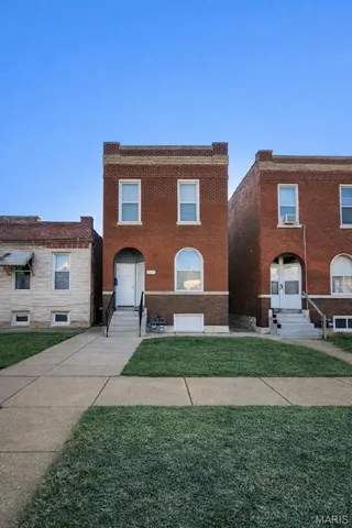 View of front of home featuring brick siding, a front lawn, and entry steps