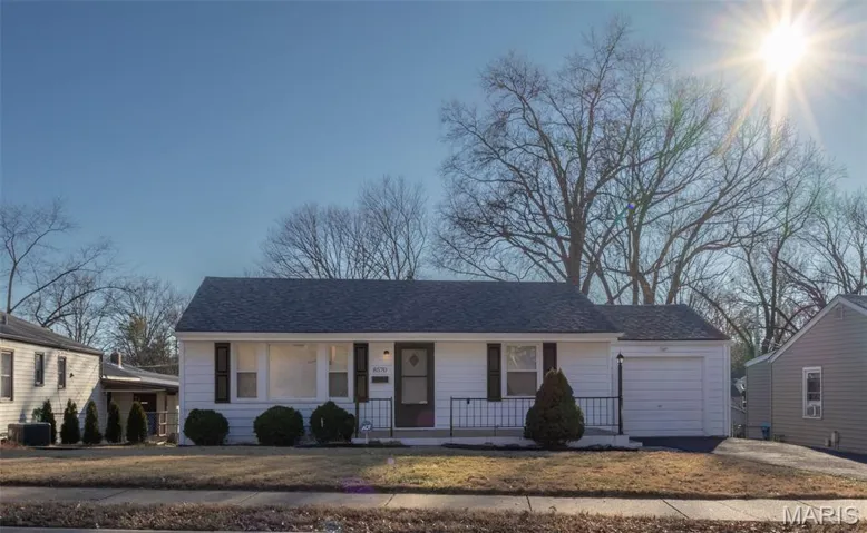 View of front of property with a porch, a shingled roof, an attached garage, concrete driveway, and a front yard