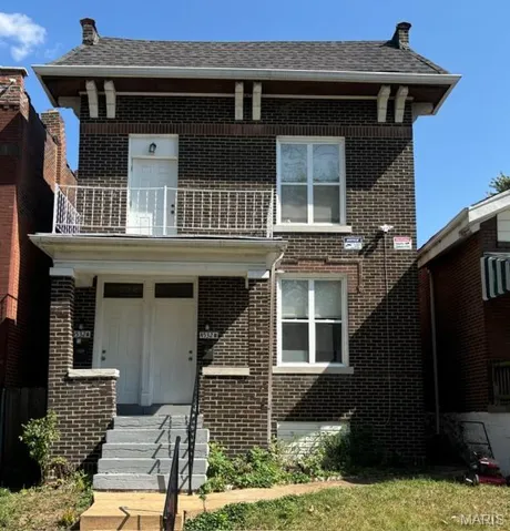 View of front facade with brick siding and a balcony