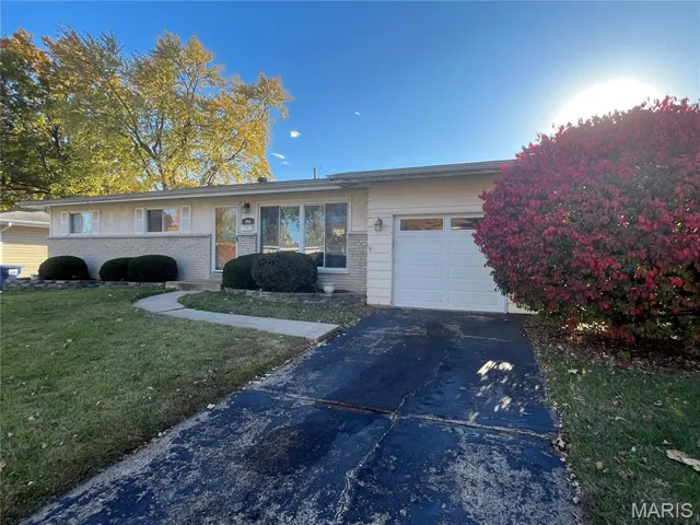 Ranch-style home featuring brick siding, concrete driveway, a front lawn, and an attached garage